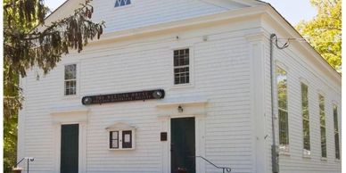 Historic white wooden church building with green doors and windows.