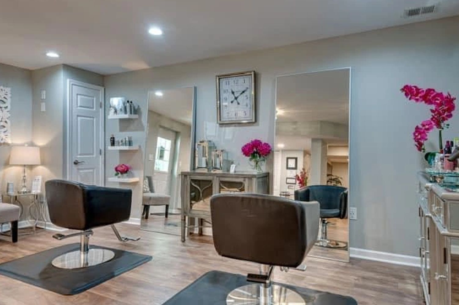 Two hairstylists posing in a salon with scissors and a glittery hairdryer.