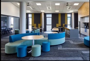 Modern office lounge with curved blue seating and round tables.