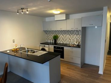 Modern kitchen with black countertop and white cabinets.