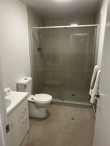 Minimalist bathroom with glass shower enclosure and white fixtures.