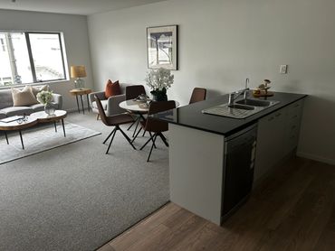 Modern open-plan living room and kitchen with neutral tones and stylish furniture.