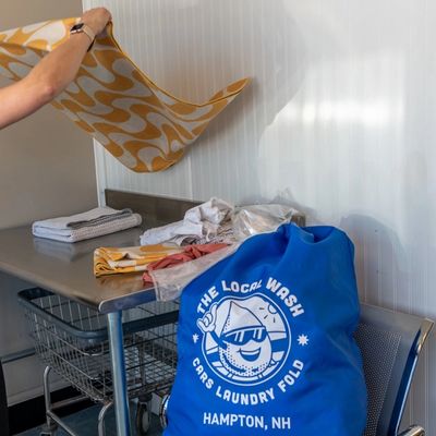 The Local Wash attendant folds a towel for a wash and fold laundry service customer.