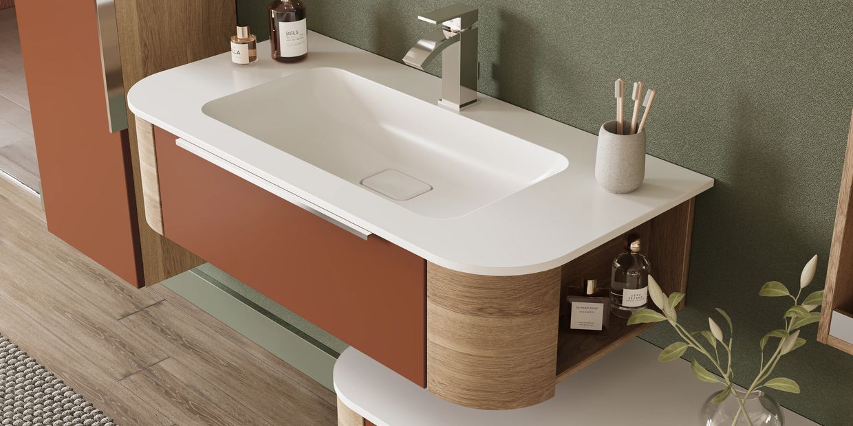 Modern bathroom sink with wooden cabinet and toiletries.