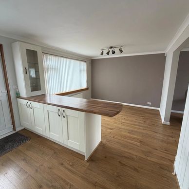 Empty modern kitchen with wooden floor and white cabinets.