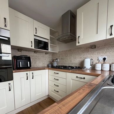 Modern kitchen with white cabinets and wooden countertops.