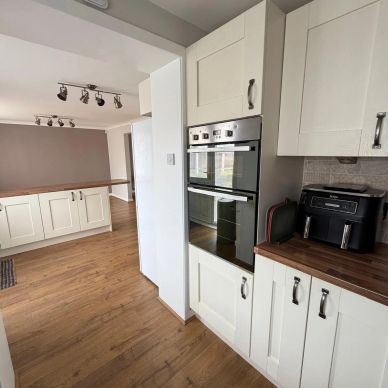 Modern kitchen with white cabinets and wooden floors.