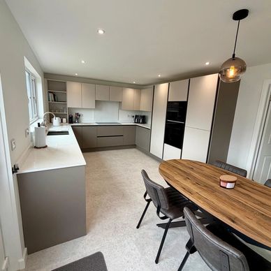 Modern kitchen with beige cabinets and a wooden dining table.