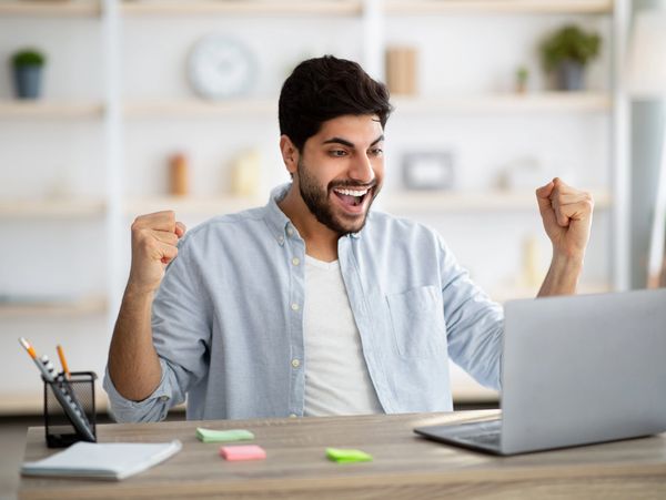 Man sat at labtop celebrating success