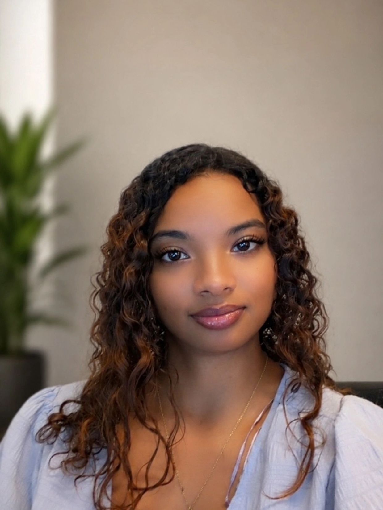 Portrait of a young woman with curly hair and a soft smile.