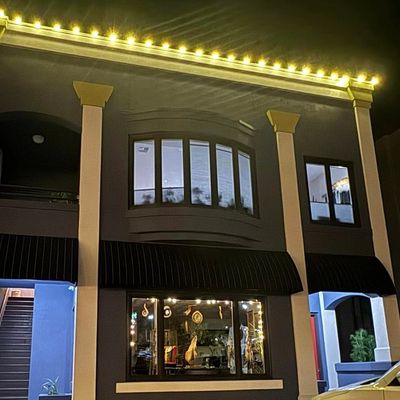 Night view of a two-story building with warm lights and a peek into the front window of ART on FIRST gallery in Ashland, OR with unique handmade gifs from local artists