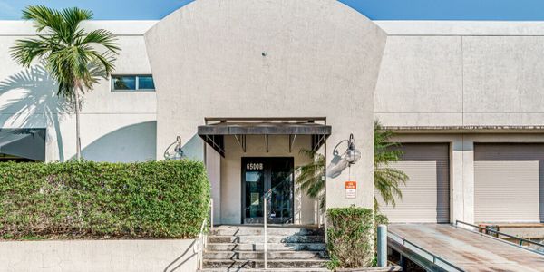 Front entrance of a commercial building with steps and greenery.