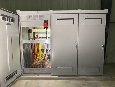 Electrical control panel with colored cables and grey cabinets.