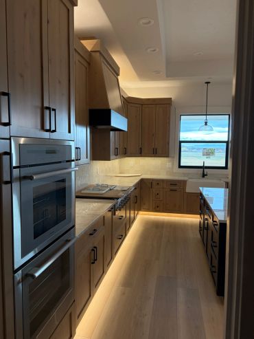 Modern kitchen with wooden cabinets and under-cabinet lighting.