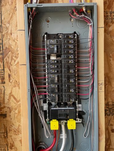 Open electrical panel with circuit breakers and wiring.