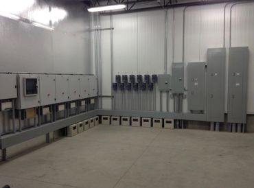 Industrial electrical panels and boxes in a clean utility room.