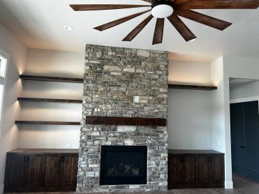Modern stone fireplace with dark wood shelves and cabinets.