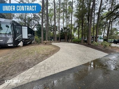 A paved RV parking spot surrounded by trees with an 'Under Contract' sign.