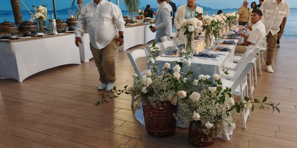 Elegant outdoor dining setup with floral decorations by the sea.