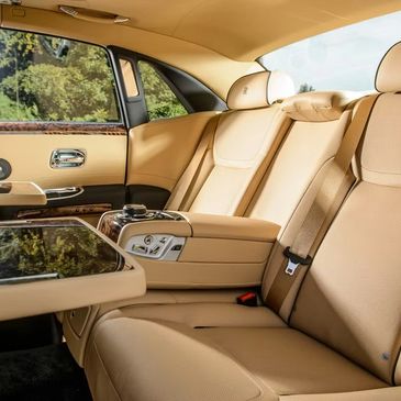 Luxurious beige leather rear seats with wood accents and a fold-out table.