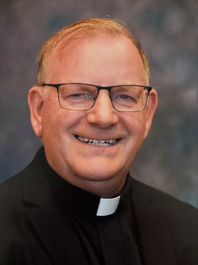 Portrait of a smiling clergyman with glasses.
