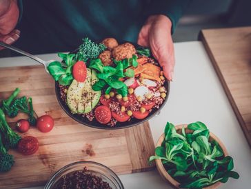 Person preparing a fresh veggie bowl