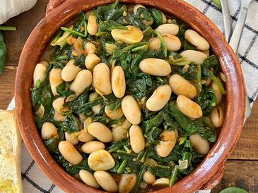 Spinach and white beans stew in a clay bowl.