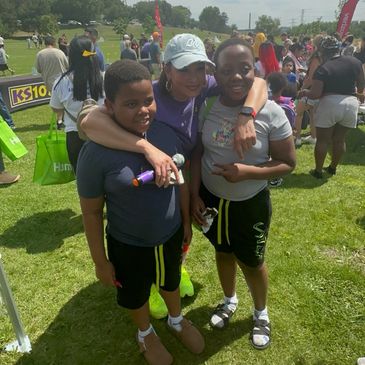 Woman hugging two boys at an outdoor event.