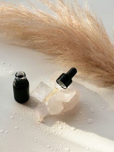 Black dropper bottle with crystals and pampas grass.