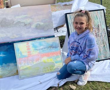 A girl kneeling next to artworks