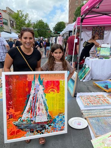 A woman and a girl holding a large painting