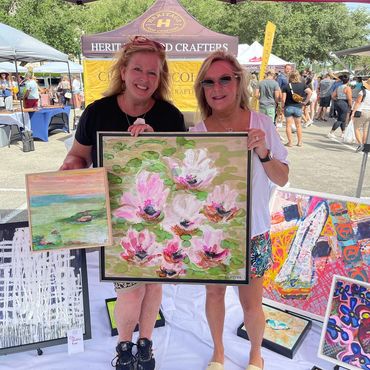 Women holding two pieces of art