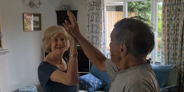 An elderly couple shares a joyful high-five in their cozy living room.