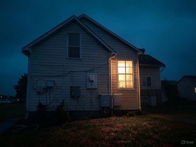 This image shows an older home with older electrical wiring a storm approaches.