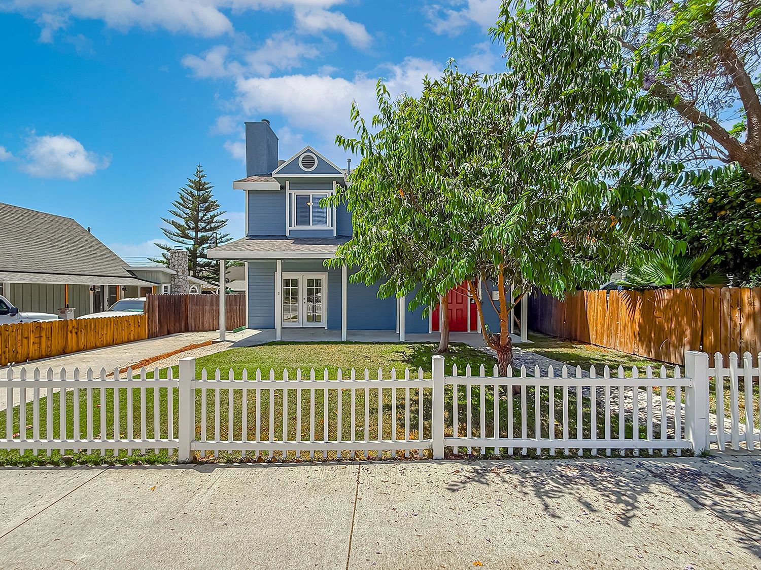 Blue house with white picket fence and green lawn.