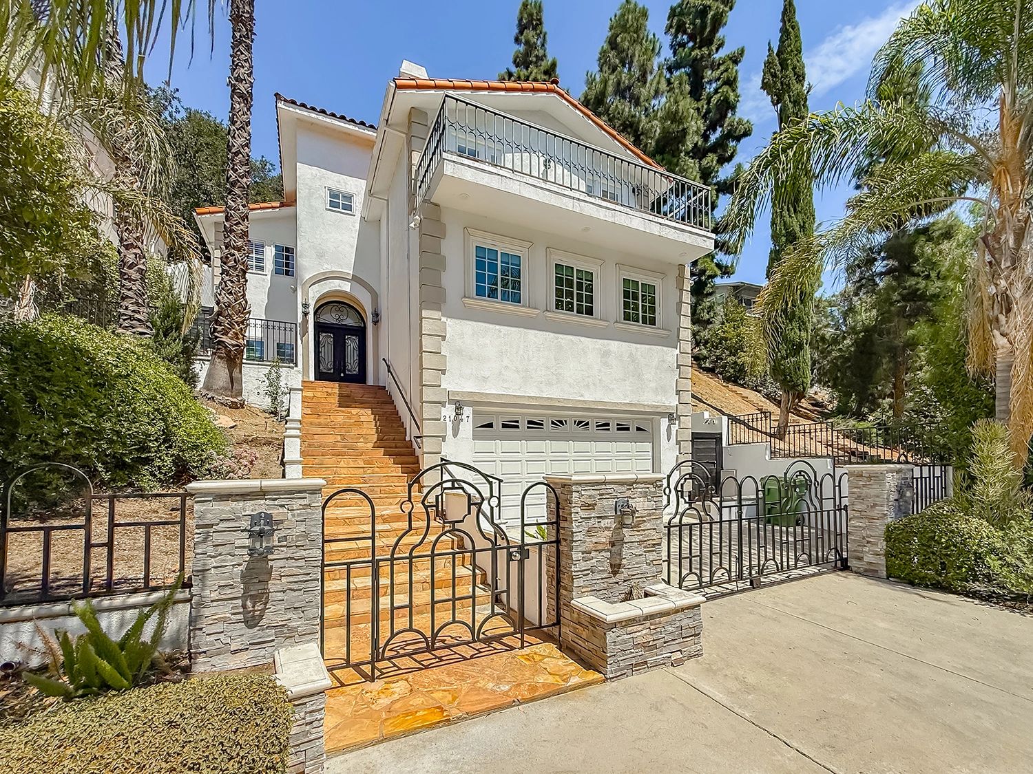 Modern white house with gated stairs and garage.