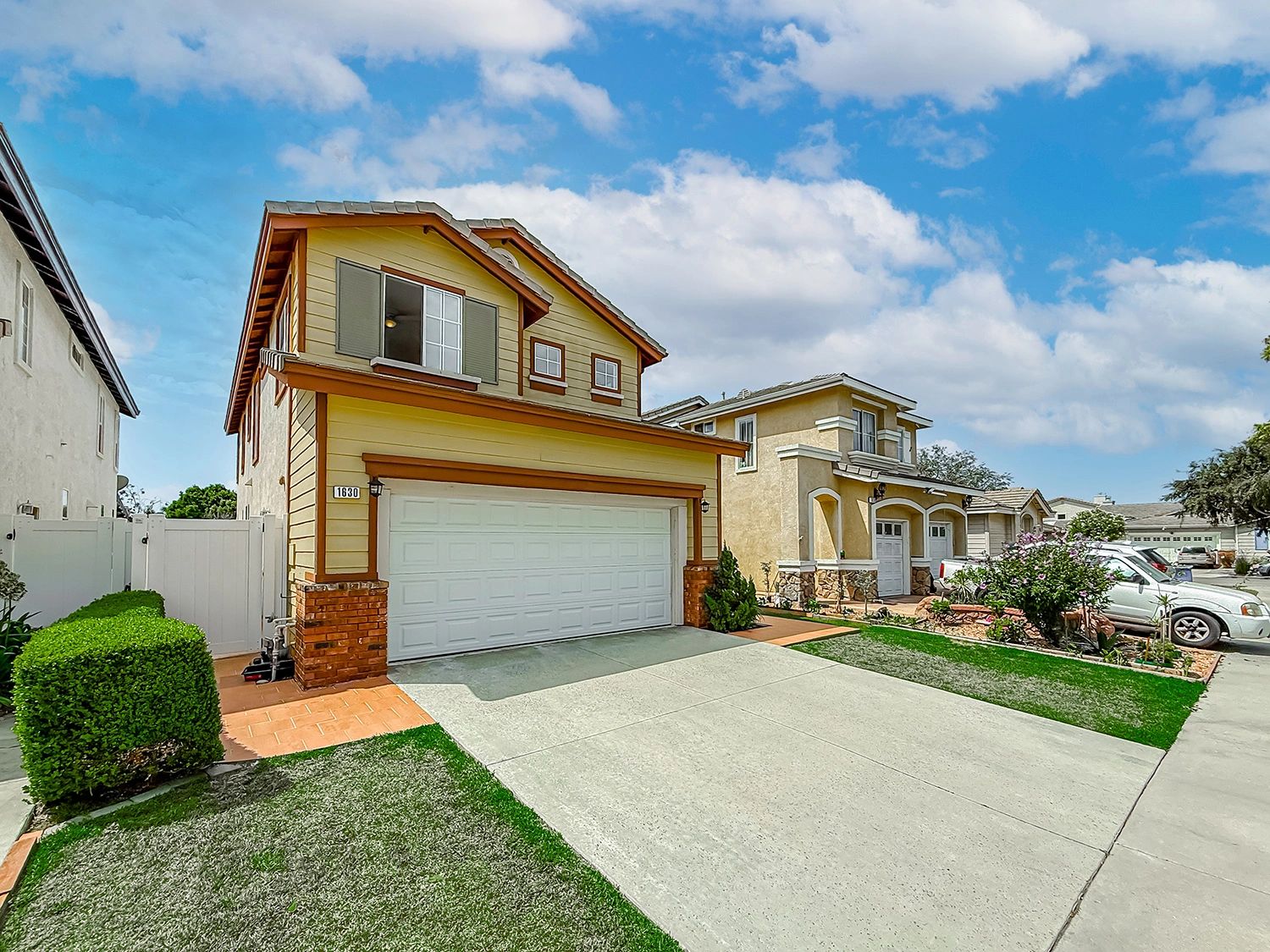 Two-story suburban house with a double garage under a clear sky.