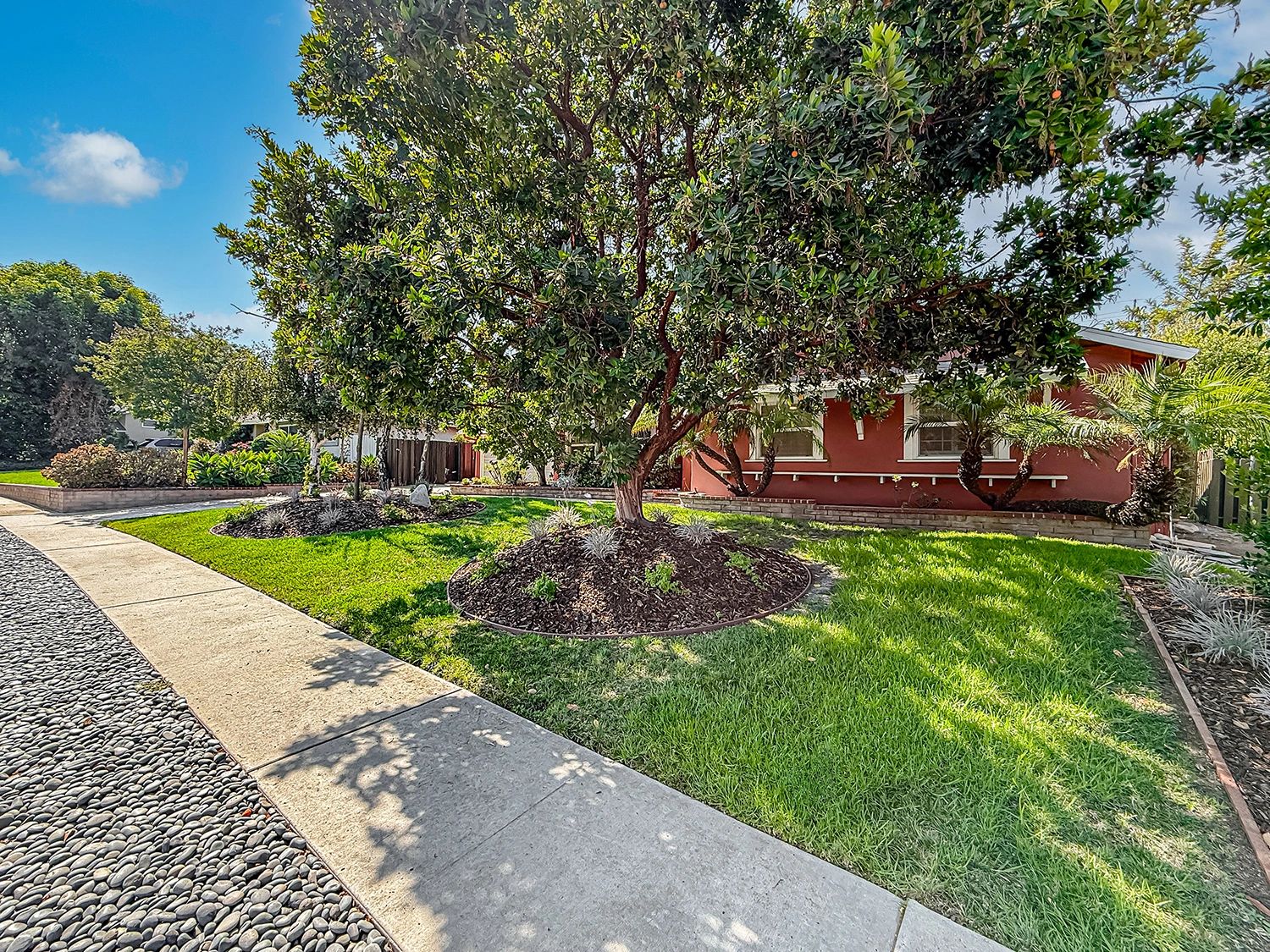 Well-maintained front yard with a large tree and green lawn.