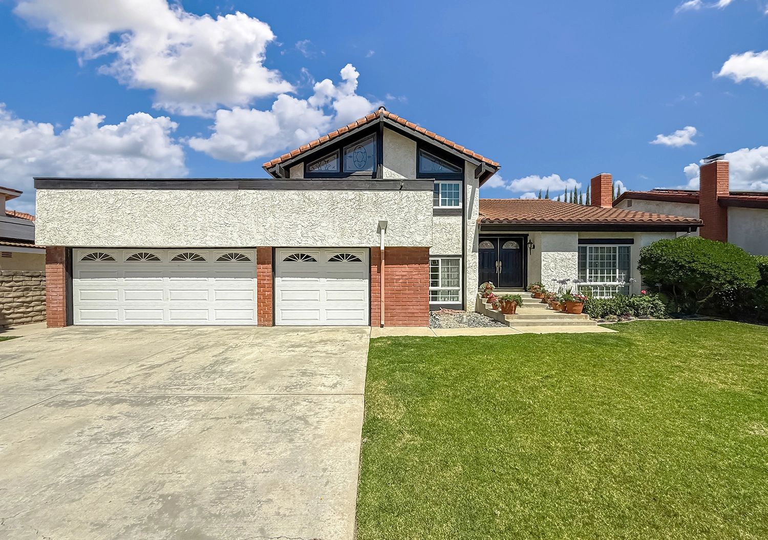 Suburban two-story house with a three-car garage and a well-maintained lawn.