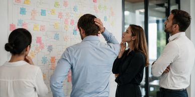 Team analyzing a board full of sticky notes in an office.