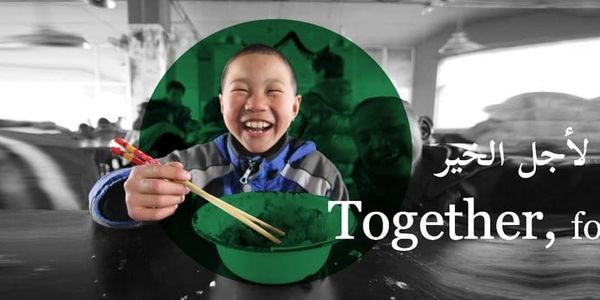 A joyful child eating with chopsticks, with the message 'Together, for good' in Arabic and English.