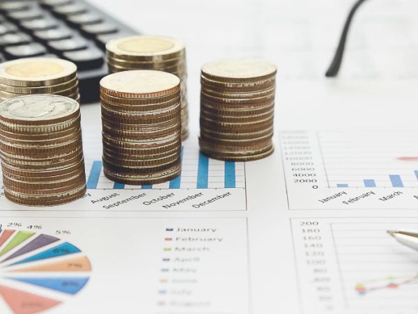 Stacks of coins on financial charts and graphs.