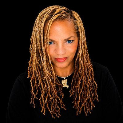 Portrait of a woman with long blond dreadlocks and blue eyes.