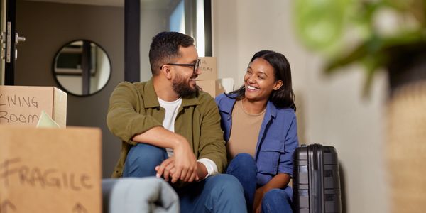 man and woman smiling with moving boxes near them