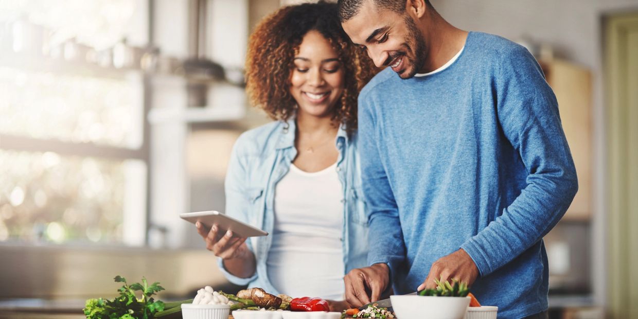 man and a woman cutting vegetables in kitchen