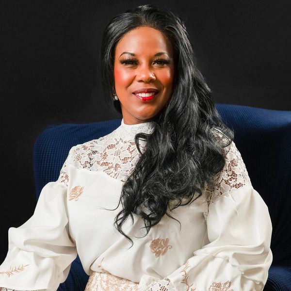 Woman in white lace top smiling.