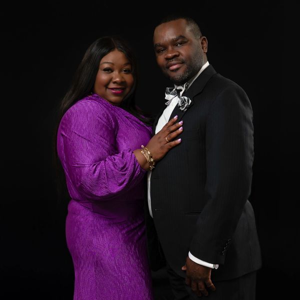 Couple posing elegantly against a black background.