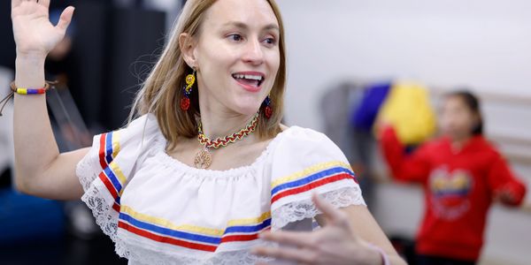 Woman joyfully dancing in traditional colorful attire with matching accessories.