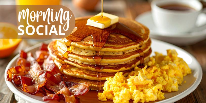 Stack of pancakes with syrup, scrambled eggs, and crispy bacon on a plate.