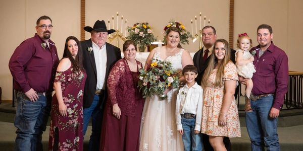 A joyful family wedding portrait with the bride holding a large bouquet.